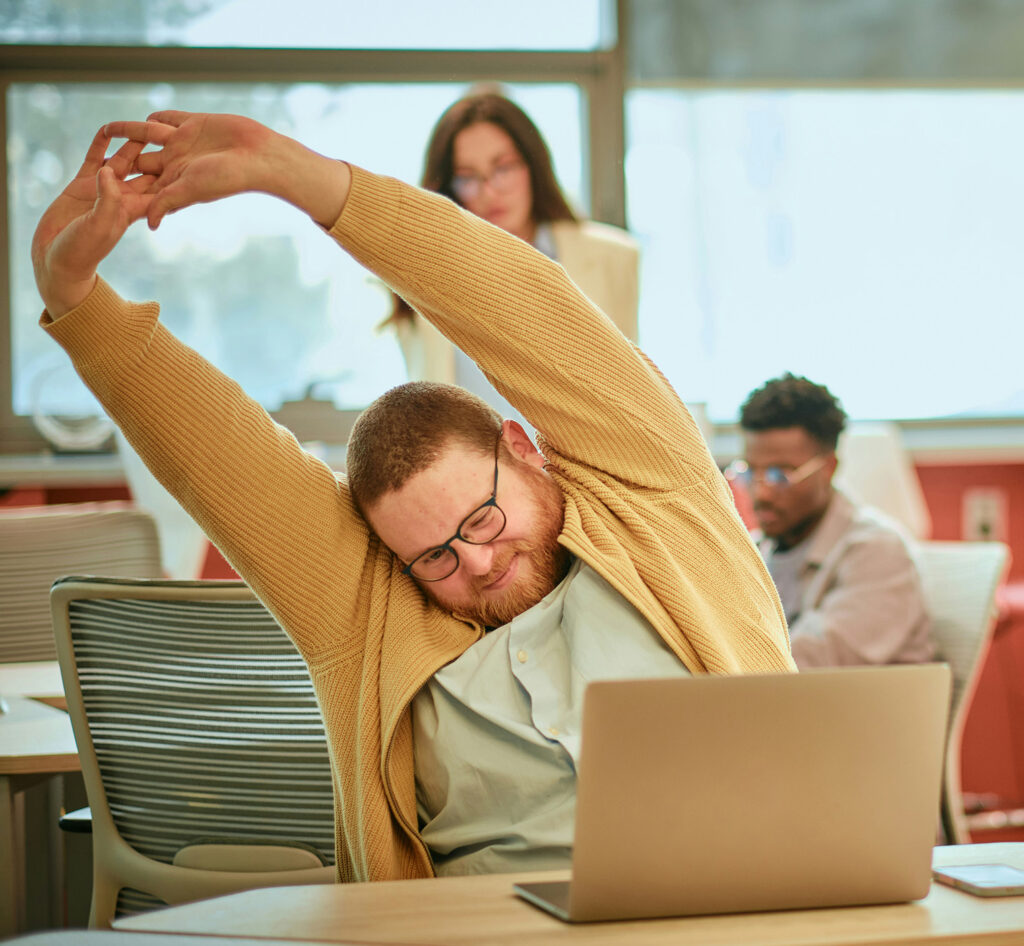 Man stretching at desk after spinal decompression for back pain