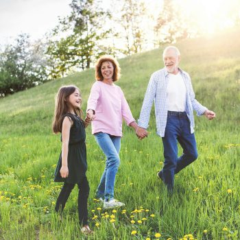 Older couple and grandchild walking in field after pain relief visit to Greenbrier Family Chiropractic in Chesapeake, VA